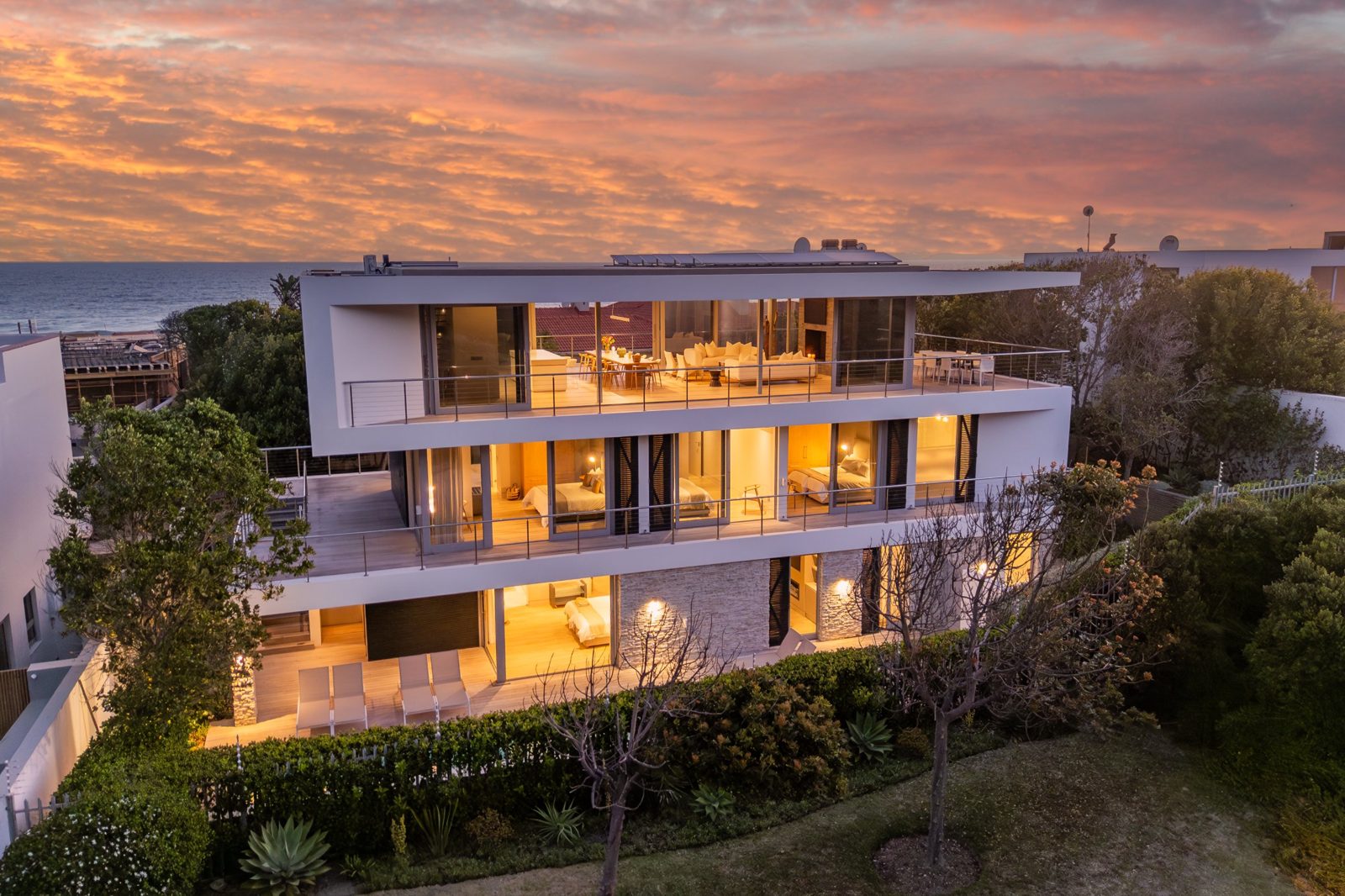 Three-storey coastal home lit up at sunset
