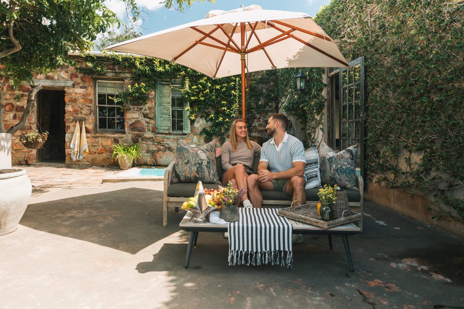 Couple relaxing under an umbrella in a stone courtyard